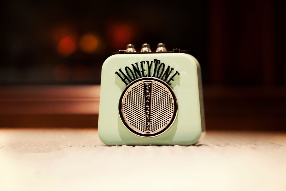 A small combo amplifier on a desk beside a guitar