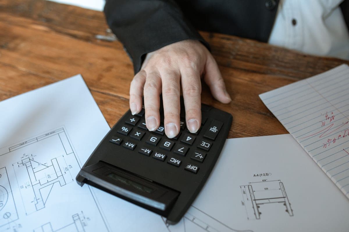 A specification sheet, a manual and a calculator on a workbench