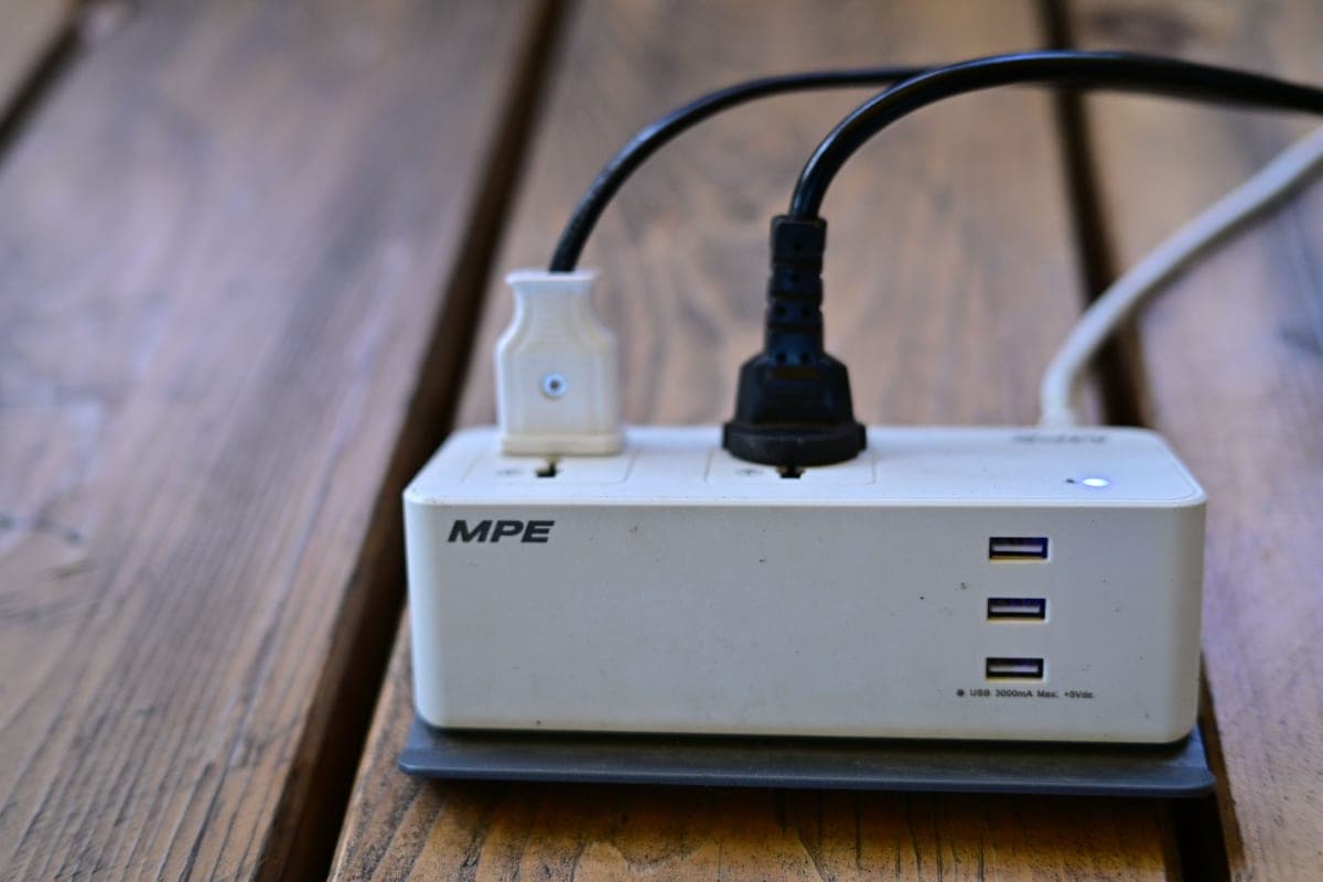 A pedalboard power supply mounted under a board with cables running out